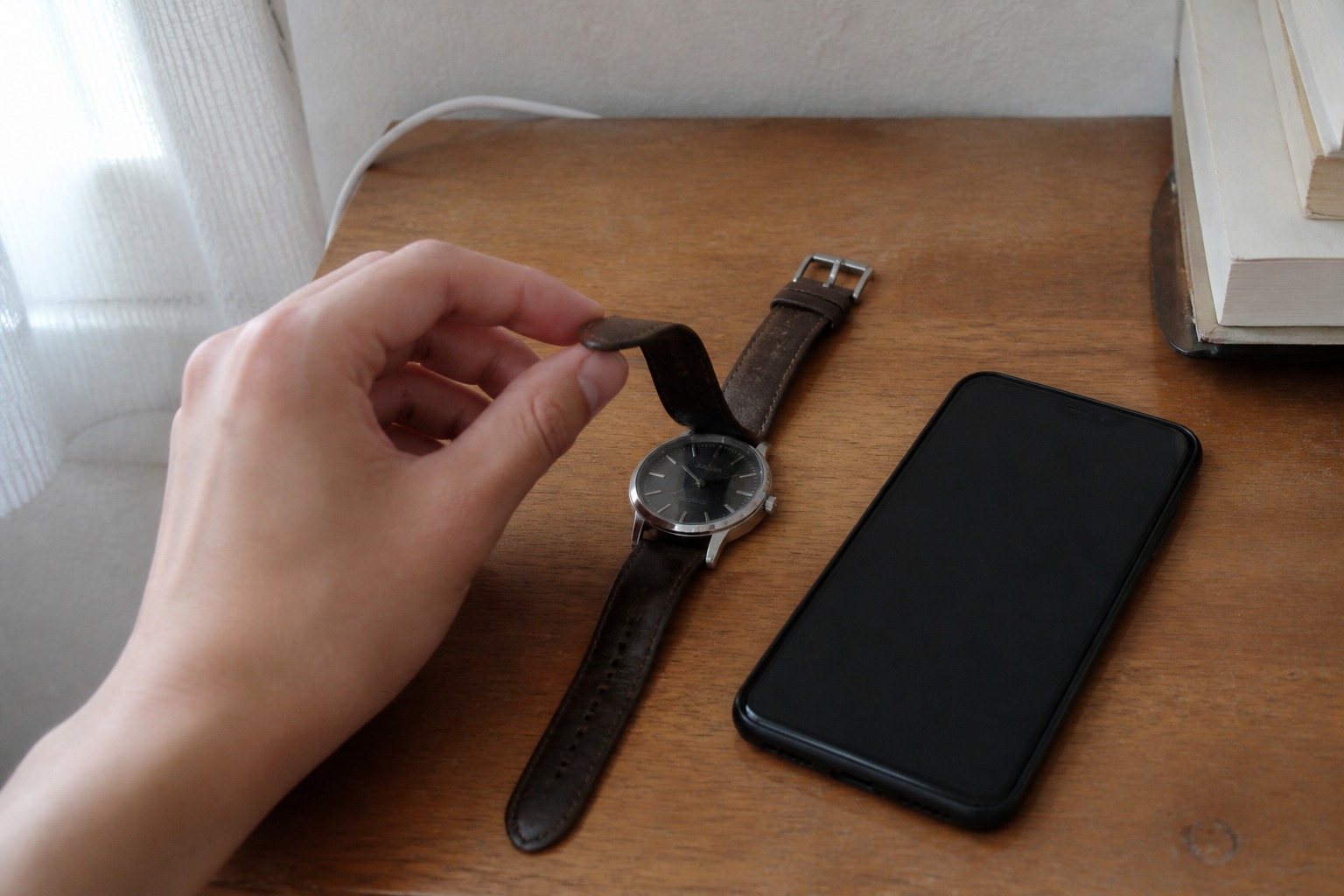 机の上で腕時計とスマホを確認する手元